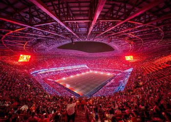 Packed Moroccan stadium at night ahead of AFCON 2025, with fans waving African flags under bright floodlights.